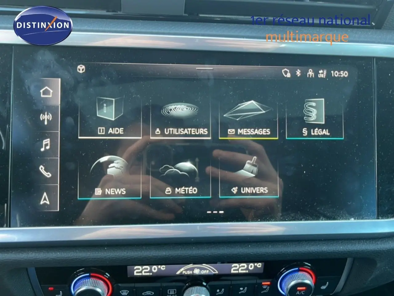 Vue intérieure centrée sur l'écran tactile et la console de climatisation du tableau de bord de l'Audi Q3 Sportback noir.