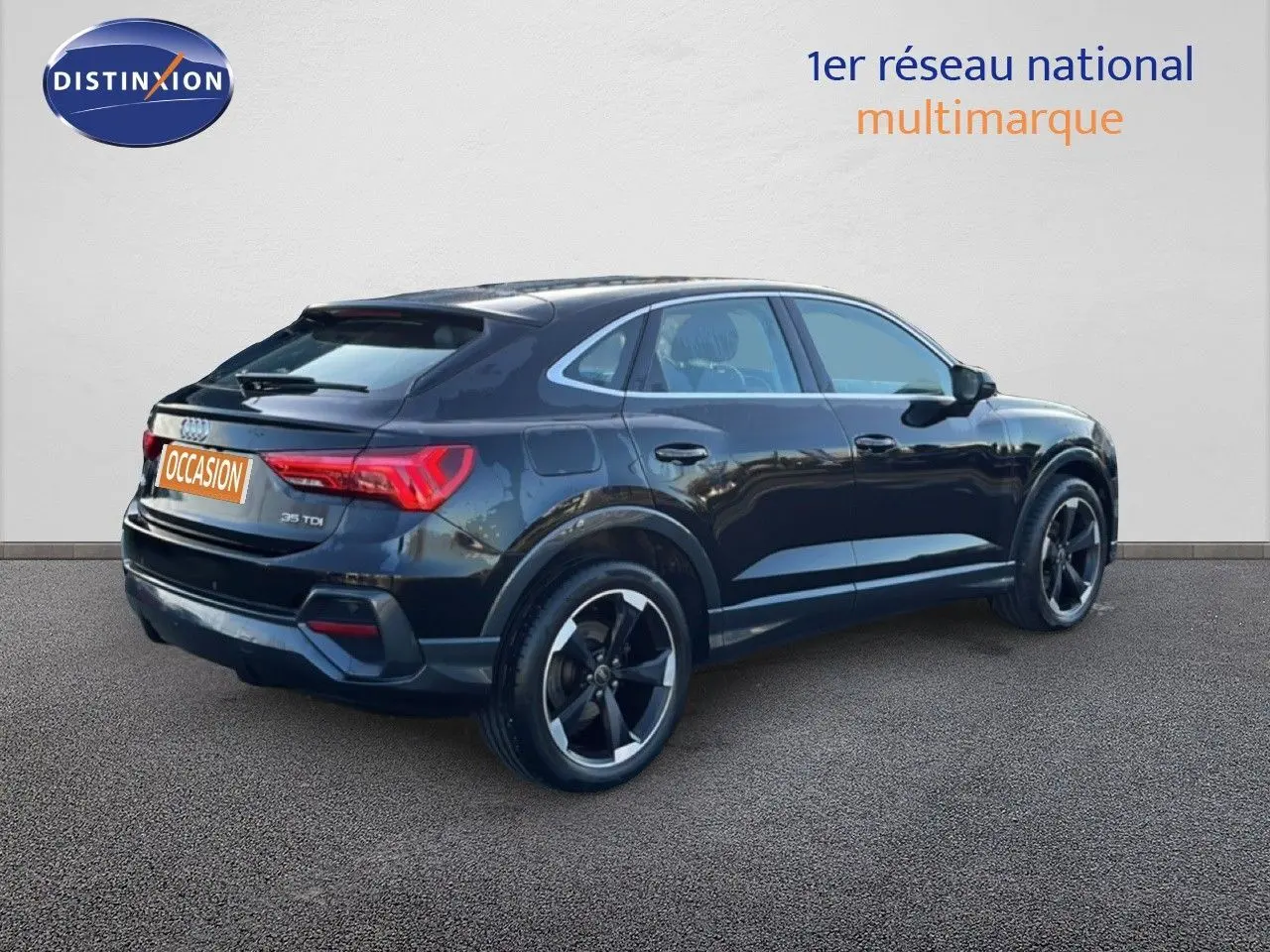 Audi Q3 Sportback noir vue 3/4 arrière côté droit, avec jantes noires distinctives et feux arrière allumés.