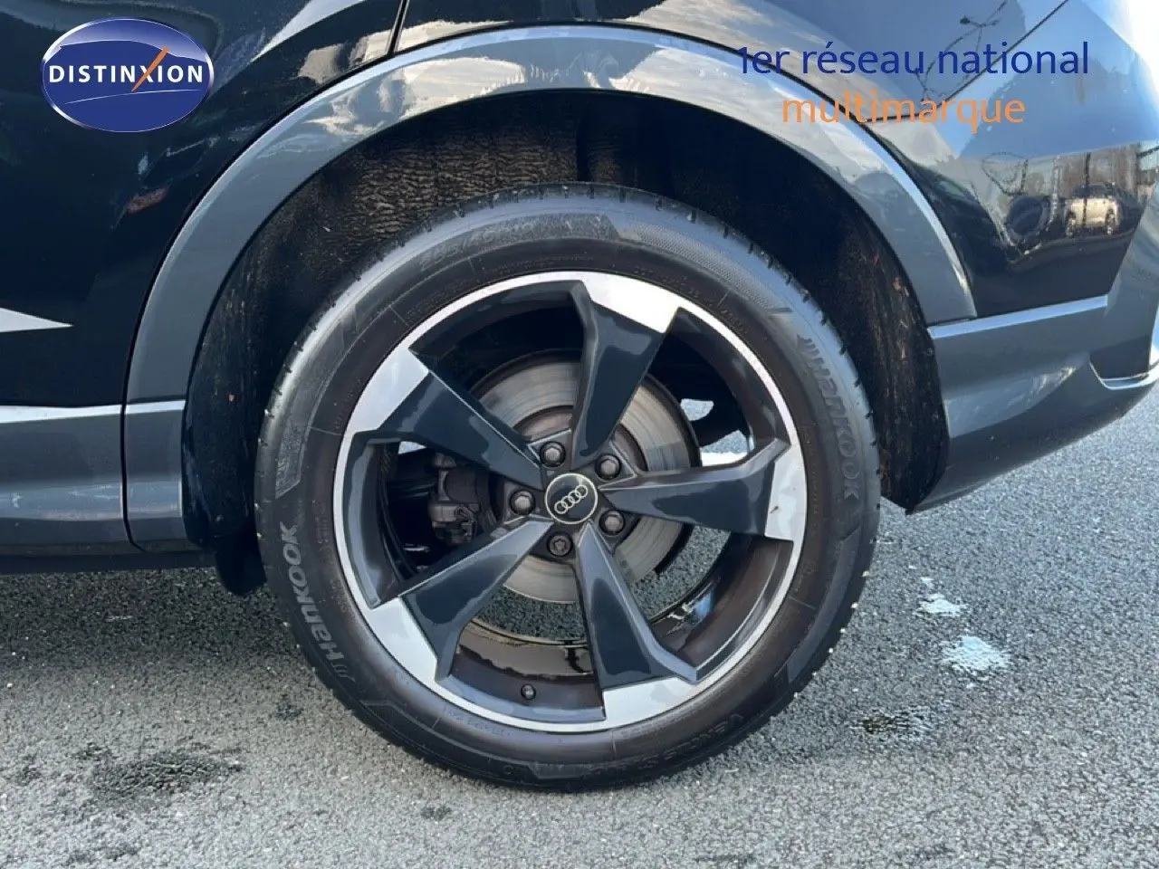Gros plan sur la roue avant droite noire d’un Audi Q3 Sportback 35 TDI 150 S-Line avec jante alliage bicolore.