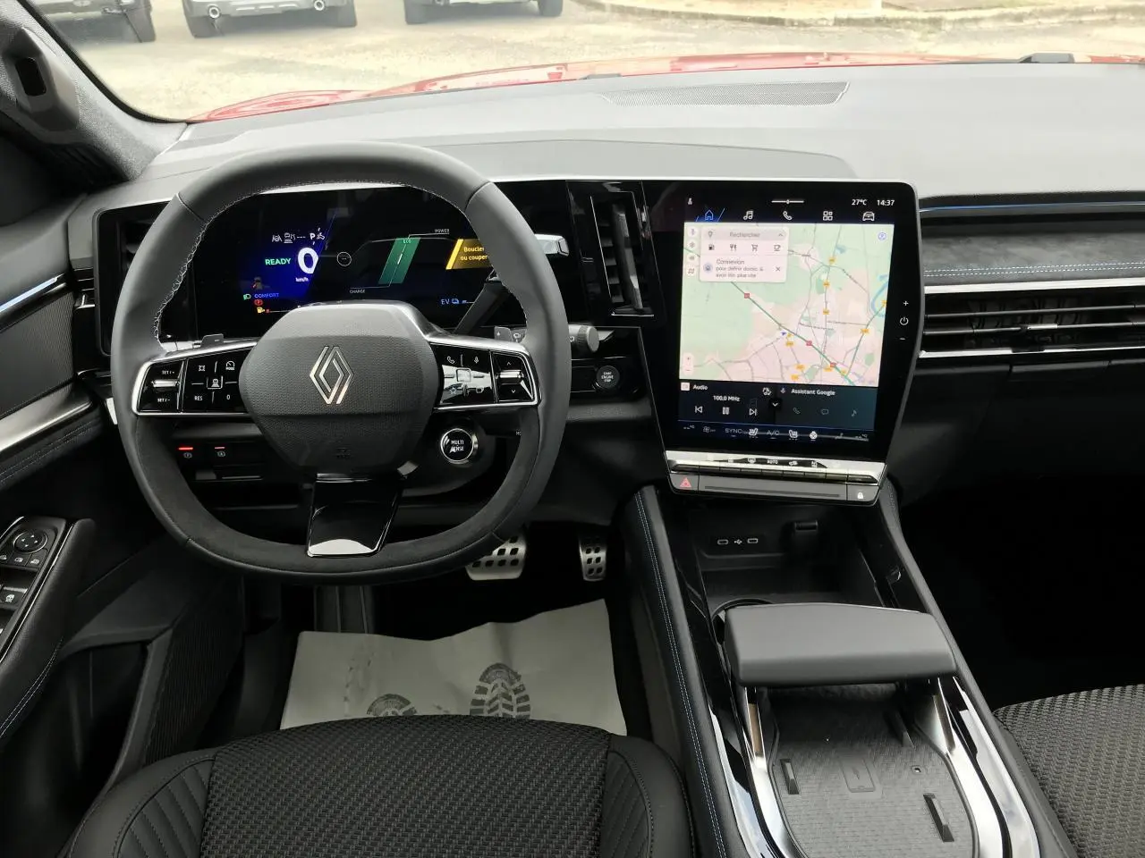 Vue intérieure frontale du tableau de bord et volant noir du Renault Austral full hybrid avec écran tactile vertical.