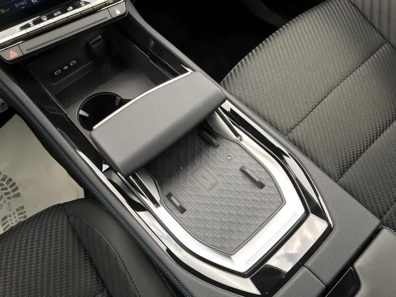 Vue rapprochée de la console centrale noire avec chargeur à induction et accoudoir sur Renault Austral rouge noir.