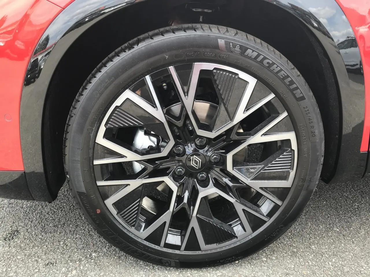 Gros plan sur la jante alliage 20 pouces noire et diamantée du côté avant gauche du Renault Austral rouge et noir.