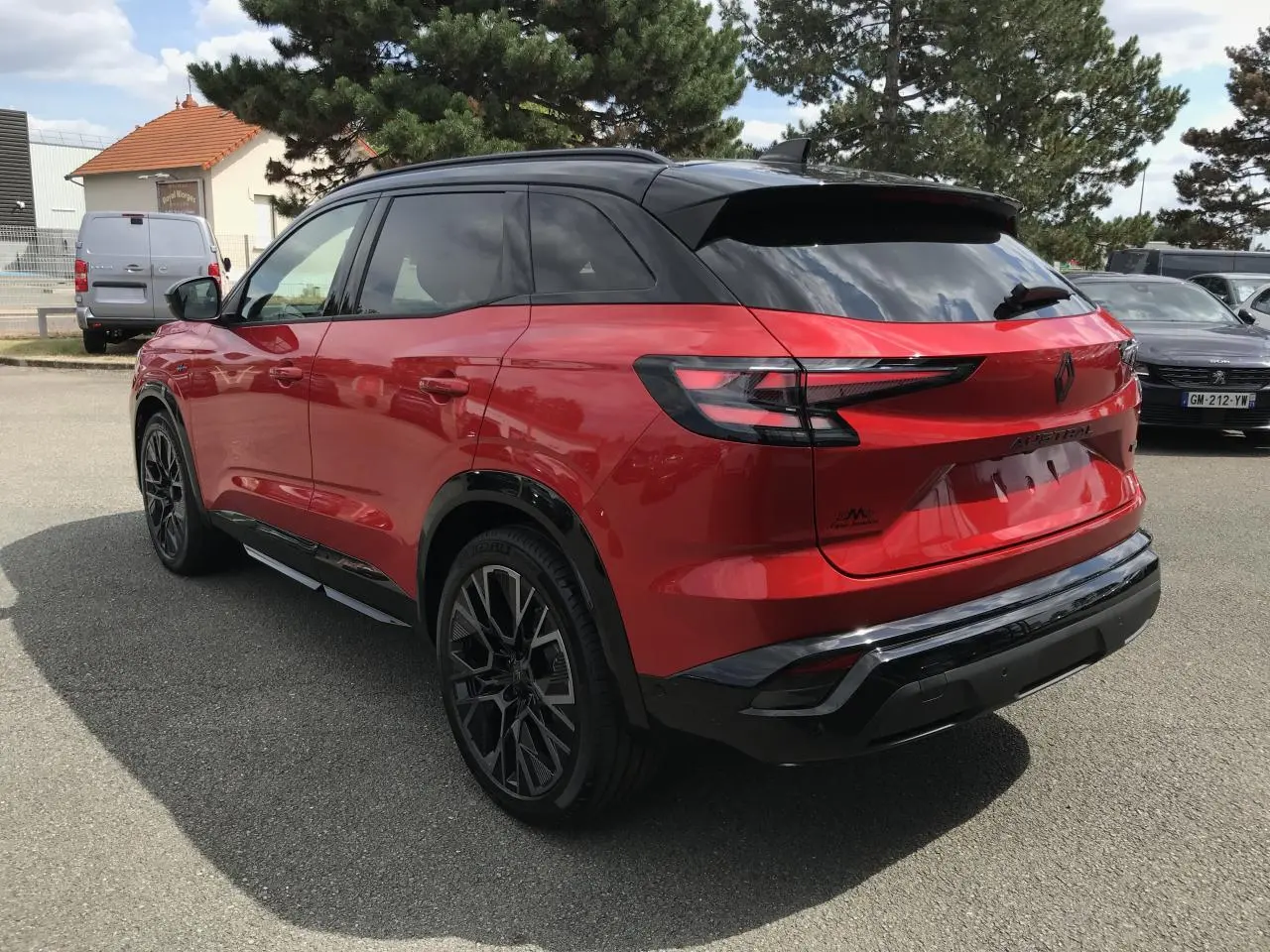Renault Austral full hybrid rouge et noir en 3/4 arrière droit, avec jantes alliage noires et toit noir brillant.