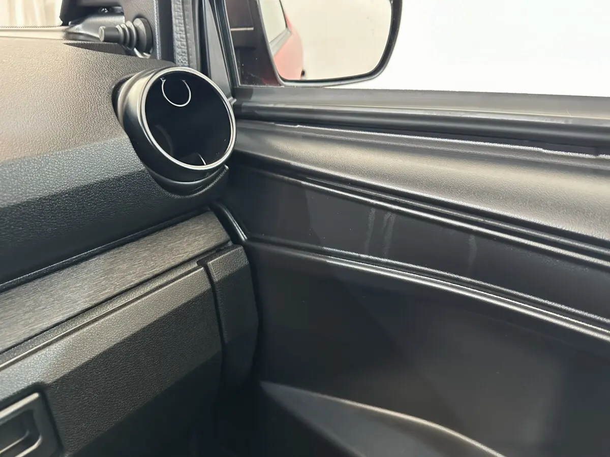 Détail intérieur côté conducteur montrant la sortie d'air ronde et le rétroviseur extérieur caméra d'une Aixam Ambition E City Pack rouge.