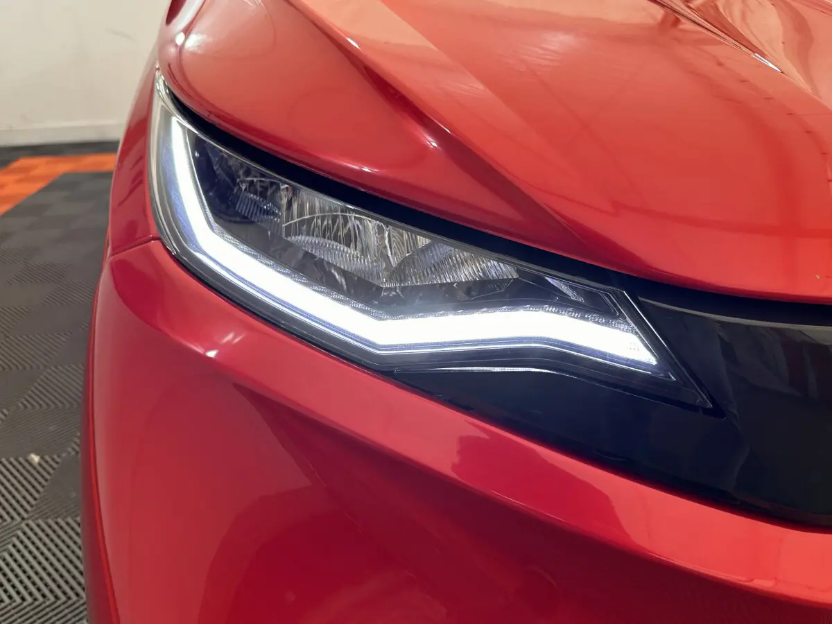 Gros plan sur le phare avant gauche d'une Aixam Ambition E City Pack rouge 2026 avec éclairage LED distinctif.