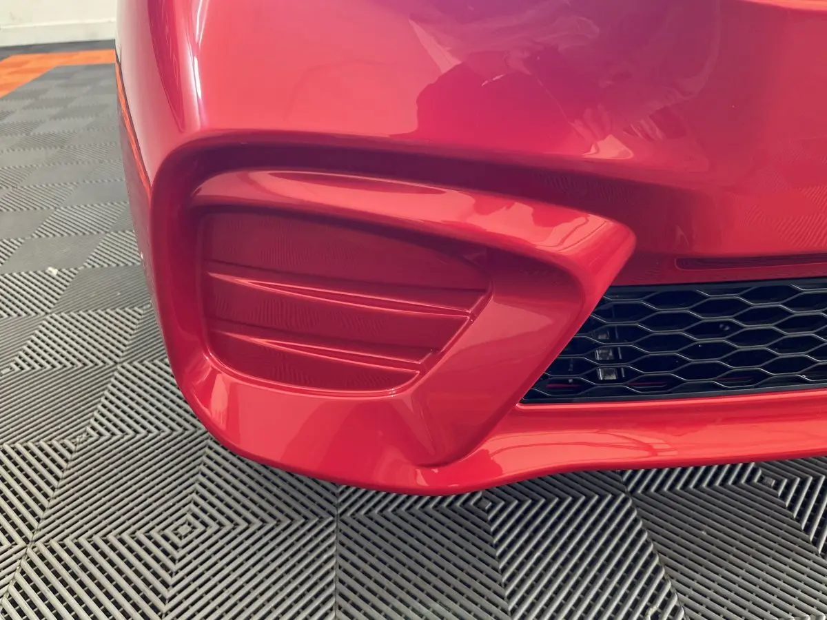 Gros plan sur le pare-chocs avant droit rouge de l'AIXAM AMBITION E CITY PACK 2026 avec grille noire ajourée.