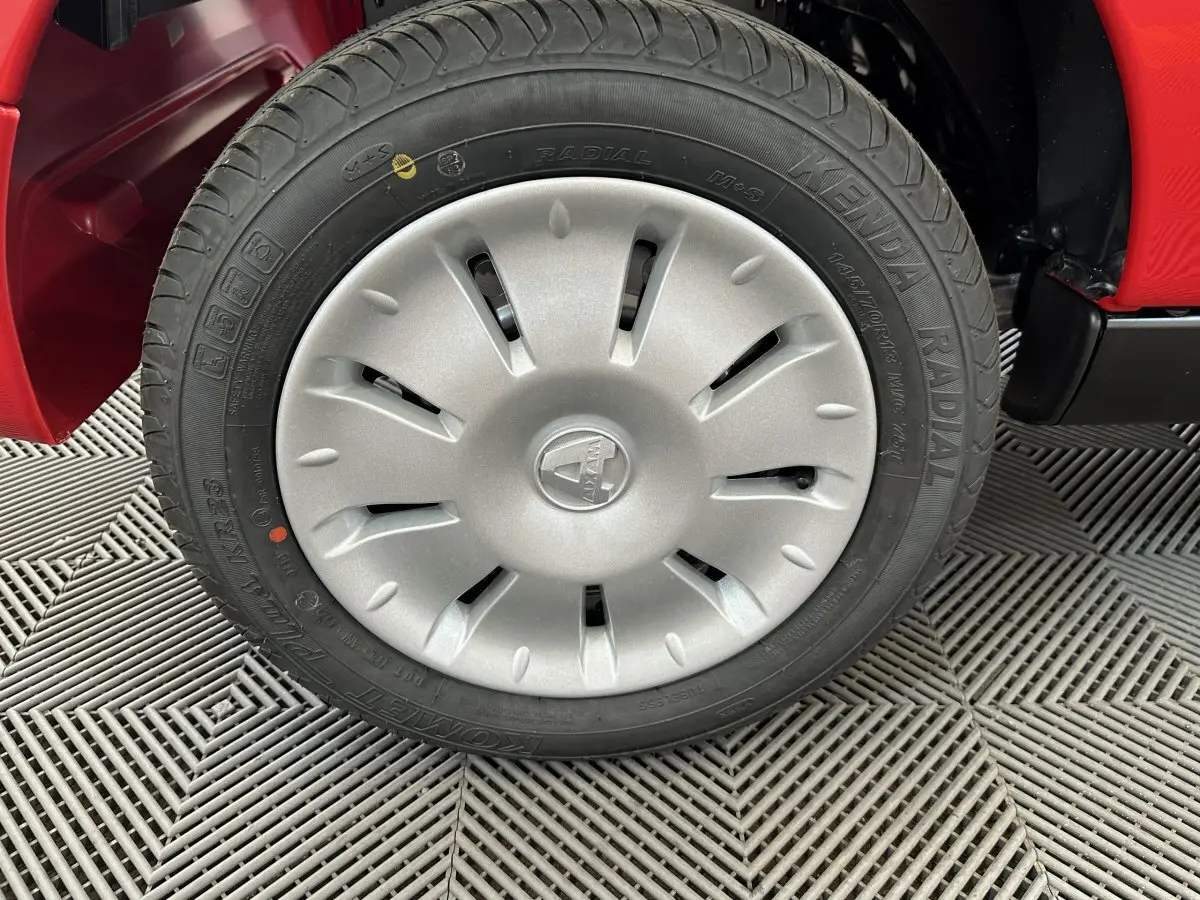 Gros plan sur la roue avant gauche d'une Aixam Ambition E City Pack rouge, mettant en valeur la jante et le pneu radial.