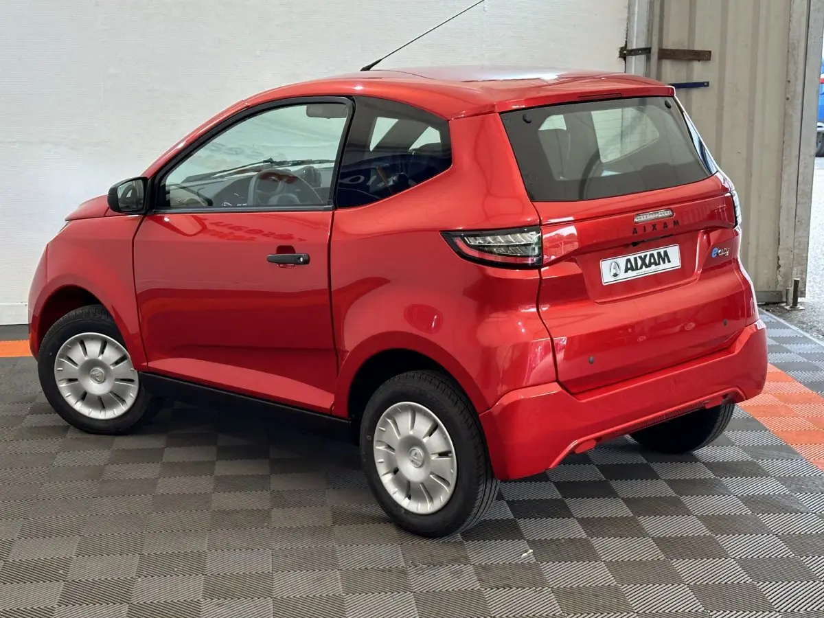 Vue 3/4 arrière droite d'une Aixam Ambition E City Pack rouge électrique avec caméras sur rétroviseurs côté conducteur.