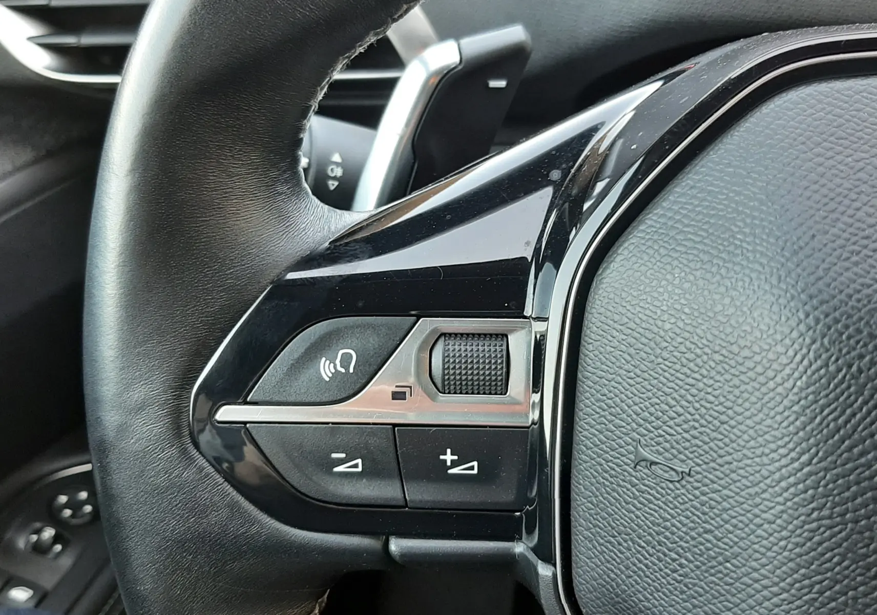 Gros plan sur la partie gauche du volant noir du Peugeot 3008 2023, avec commandes audio et finition brillante.