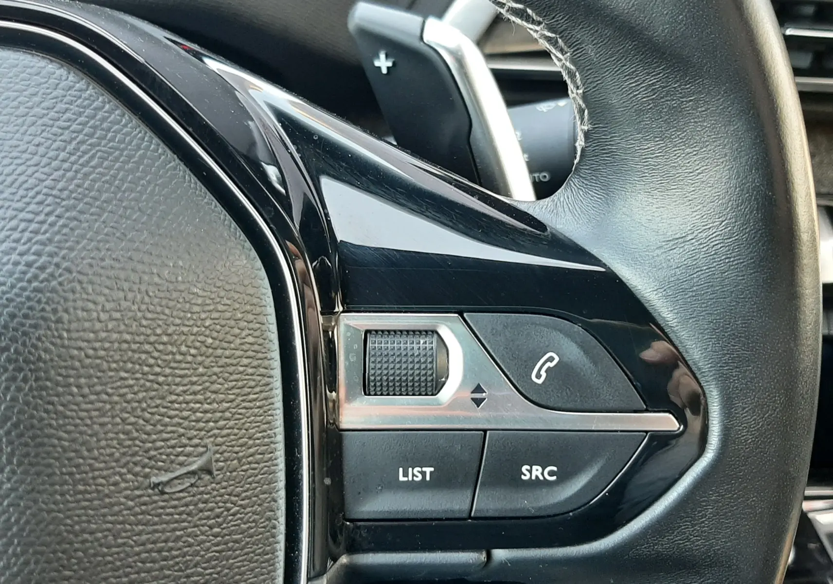 Gros plan sur la partie droite du volant en cuir noir du Peugeot 3008 2023, avec commandes intégrées et palettes de changement de vitesse.