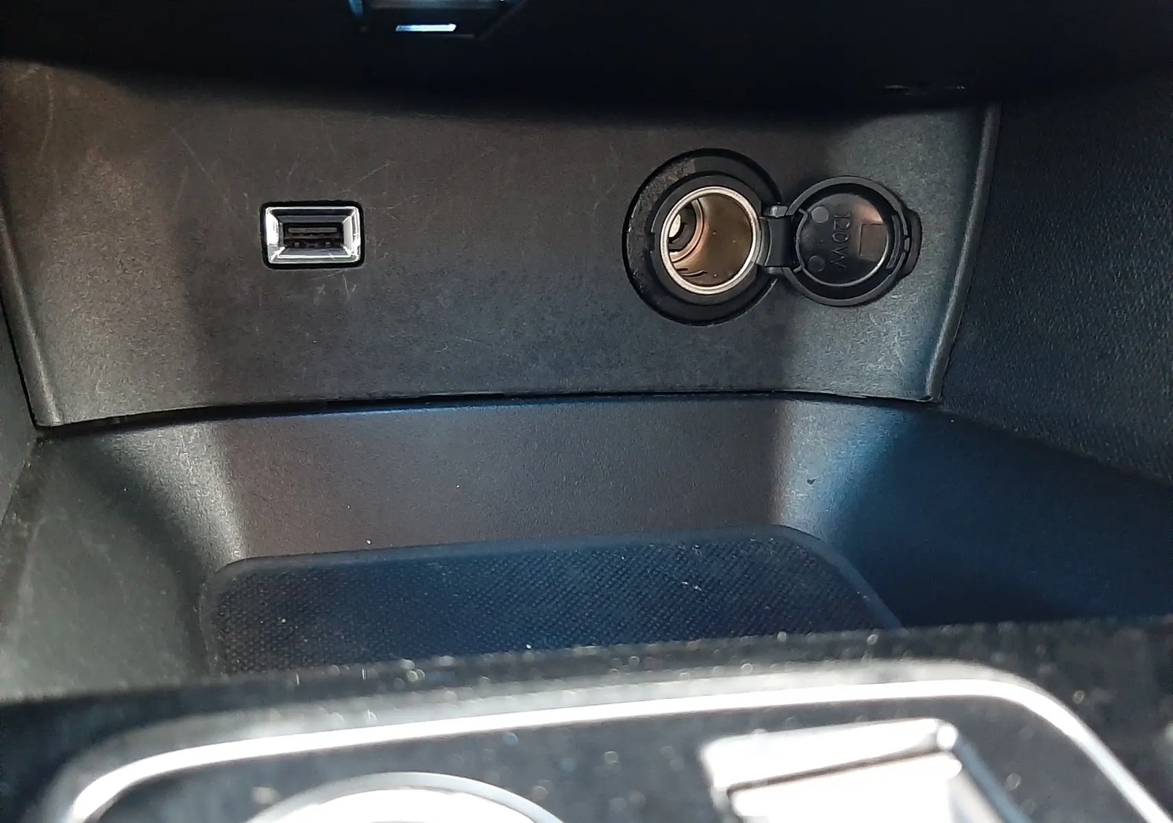 Prise USB et allume-cigare ouverts dans l’espace de rangement central du Peugeot 3008 gris platinium 2023.