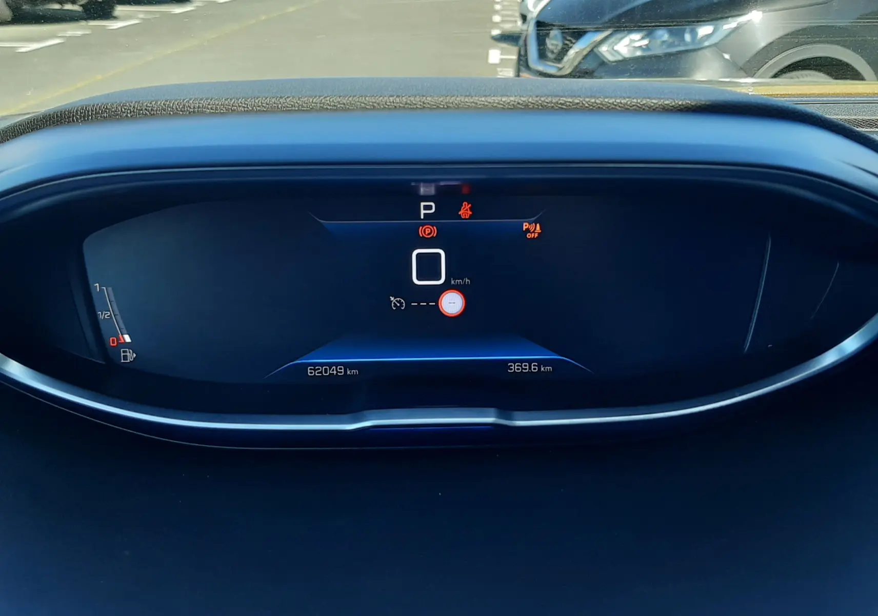 Vue intérieure du tableau de bord numérique du Peugeot 3008 gris, affichant la vitesse à zéro et le mode parking activé.