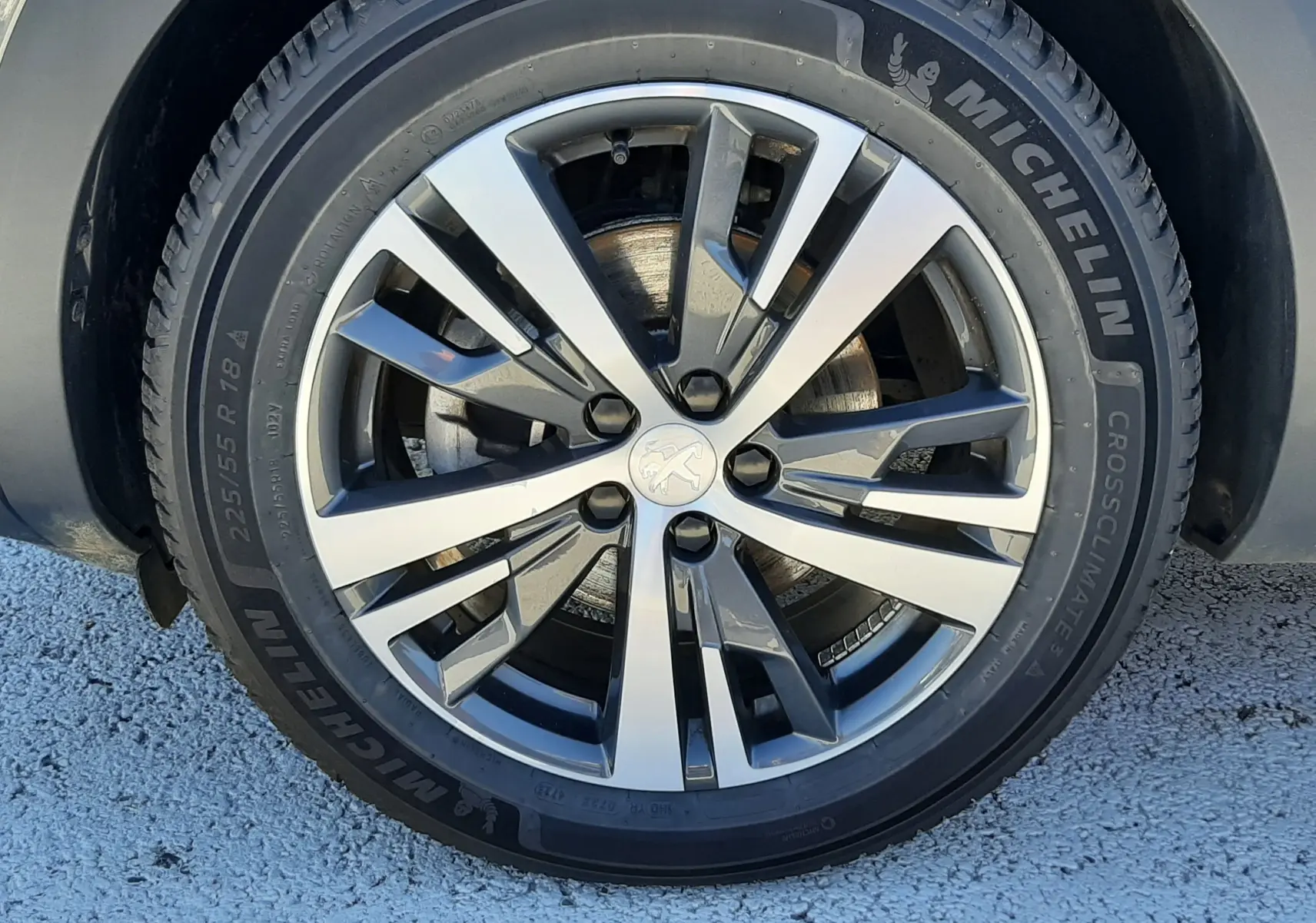 Gros plan sur la roue avant droite d’un Peugeot 3008 gris platinium, jante alliage bicolore et pneu Michelin.