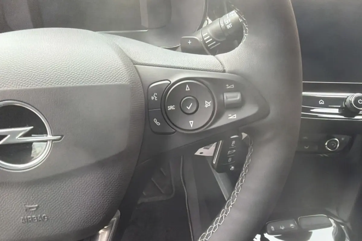 Gros plan sur le volant cuir multifonctions de l’Opel Corsa Hybrid 2026, avec commandes intégrées et tableau de bord noir.