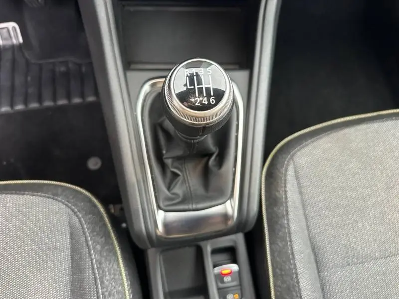 Gros plan sur le levier de vitesse manuel du Renault Captur 2025, entouré des sièges en tissu gris.