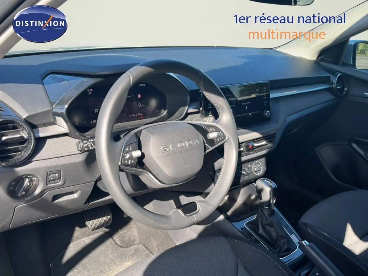 Vue intérieure du poste de conduite d'une Skoda Fabia 2025, tableau de bord et volant en gris noir, avec boîte automatique.