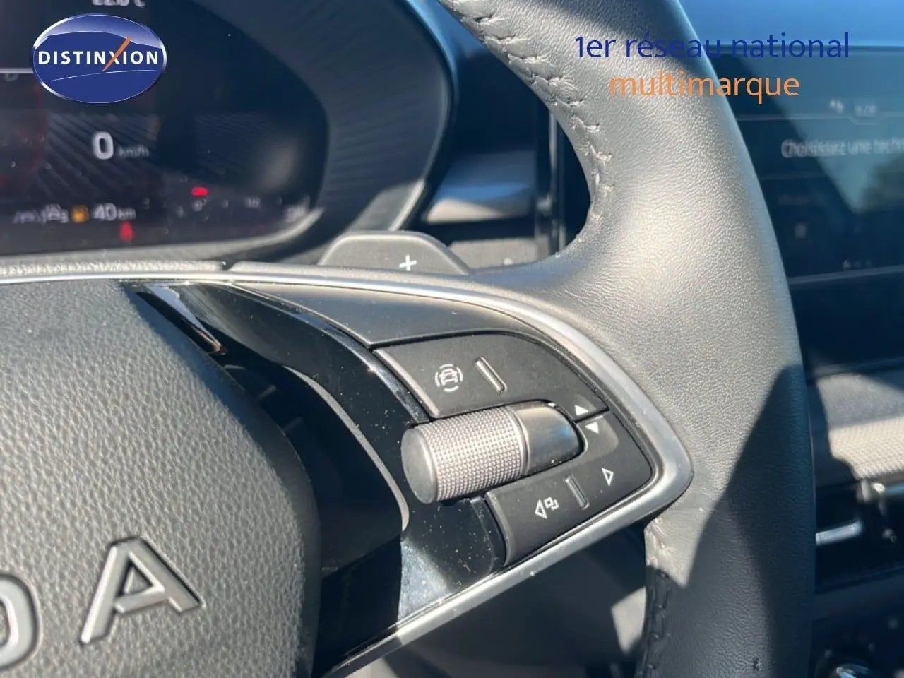 Gros plan sur les commandes au volant en cuir noir de la Skoda Fabia 2025, avec molette et boutons multifonctions.