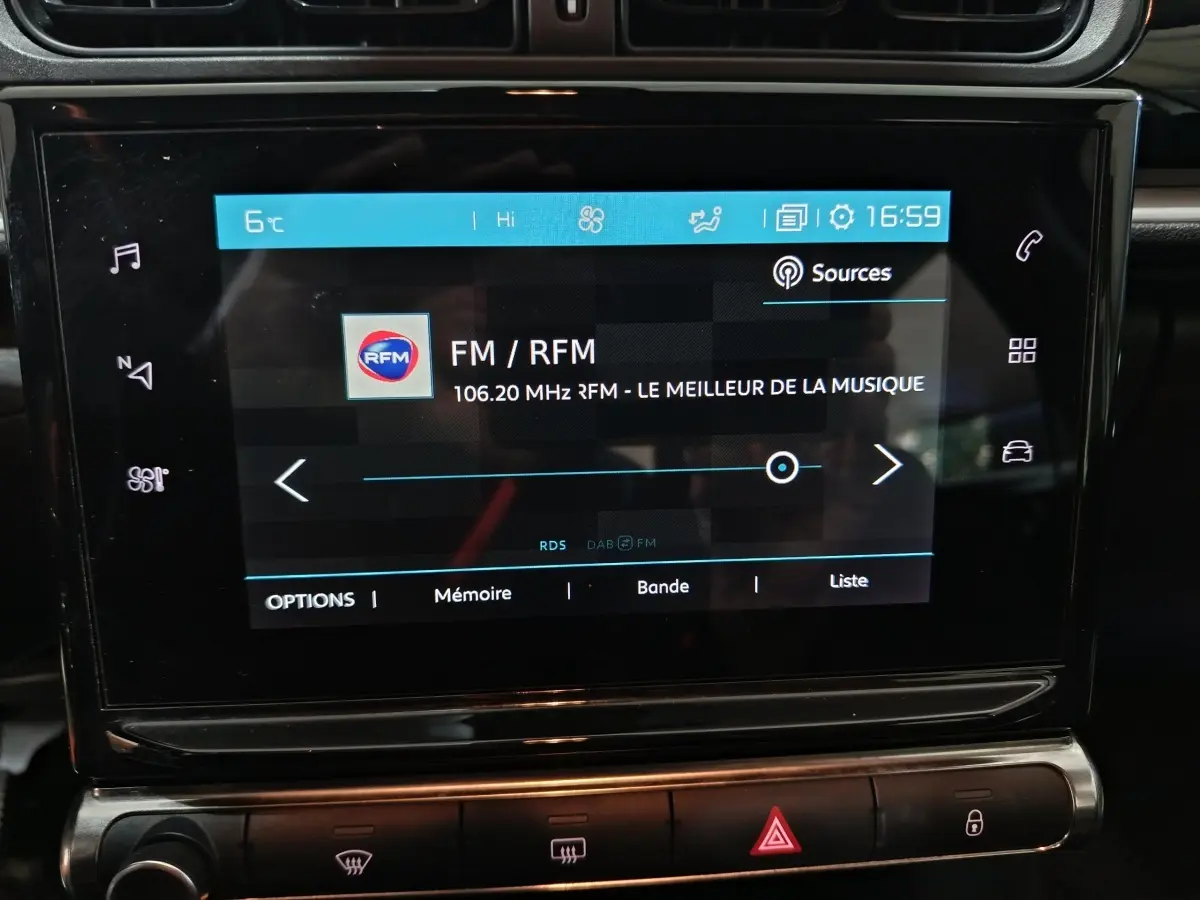 Écran tactile central de la Citroën C3 gris foncé 2024 affichant la radio FM avec commandes tactiles et boutons en dessous.