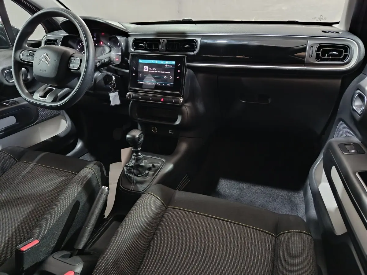 Vue intérieure côté conducteur de la Citroën C3 2024 gris foncé, avec tableau de bord central tactile et volant multifonctions.