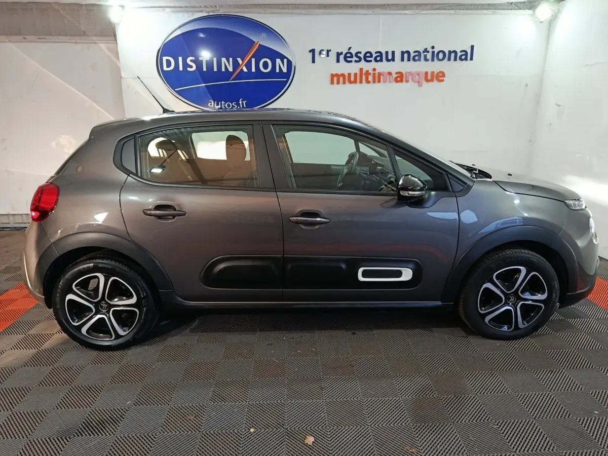 Vue latérale droite d'une Citroën C3 2024 gris foncé avec protections latérales noires et jantes alliage bicolores.