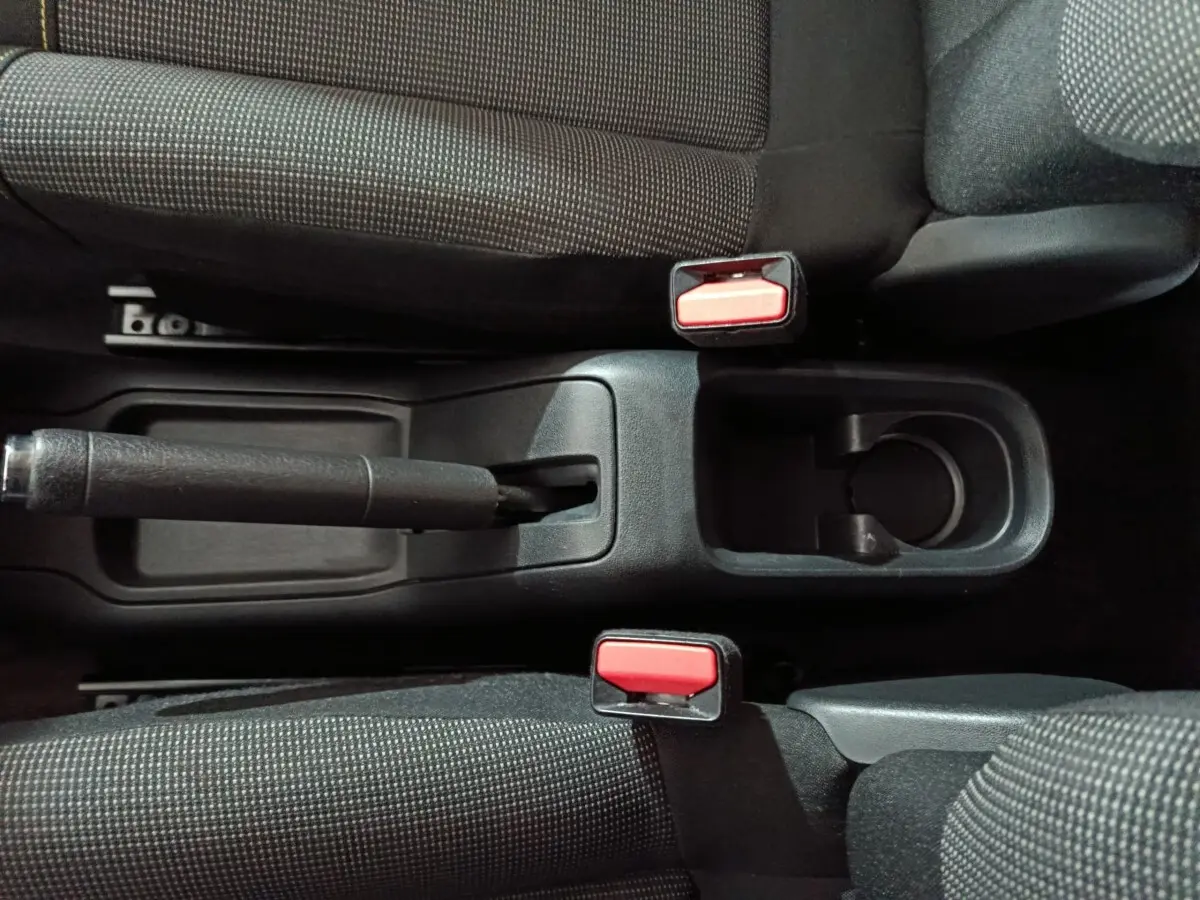 Vue plongeante sur la console centrale noire de la Citroën C3 2024, avec frein à main manuel et ceintures rouges.