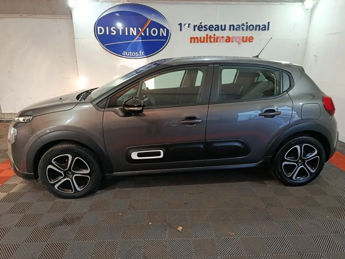 Profil droit d'une Citroën C3 BlueHDi 100 gris foncé 2024 avec jantes noires et inserts blancs sur les portes.