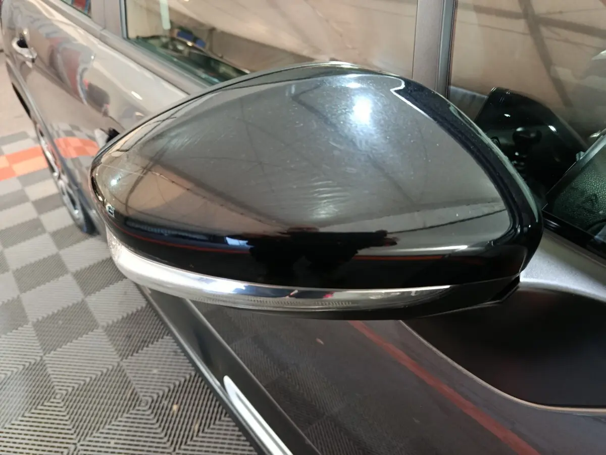 Gros plan sur le rétroviseur droit noir brillant d'une Citroën C3 gris foncé 2024, avec clignotant intégré.