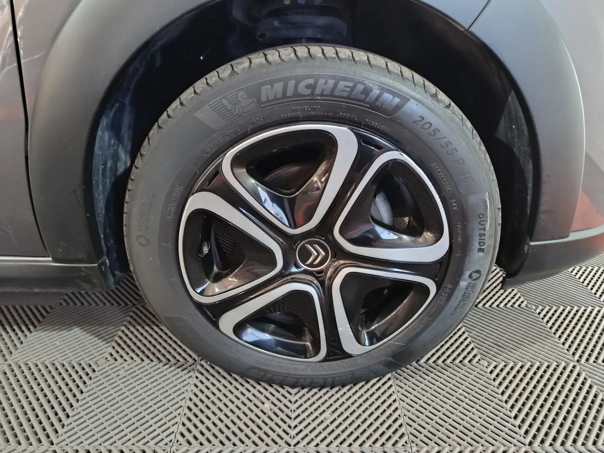 Gros plan sur la roue avant droite d'une Citroën C3 gris foncé, jante noire et argent avec logo Citroën central.