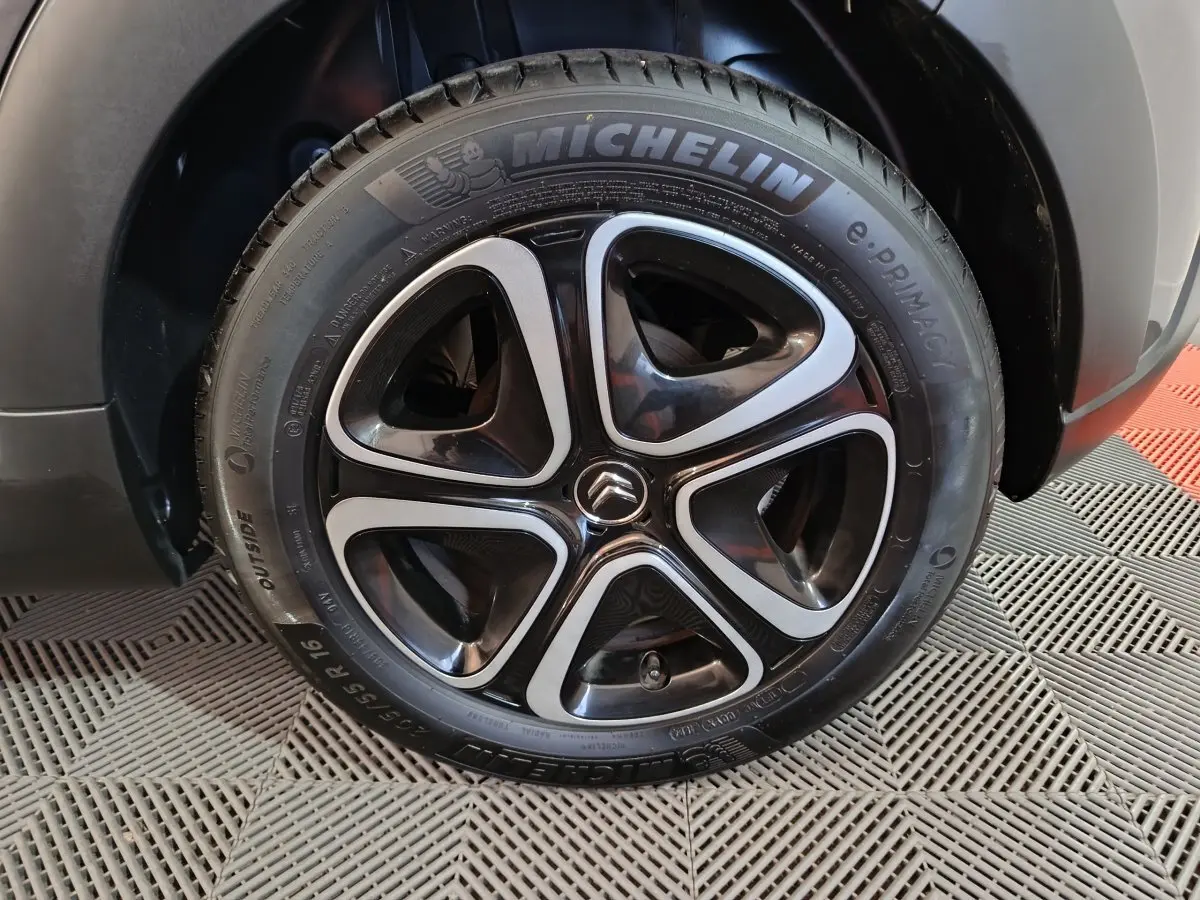Gros plan sur la roue avant droite d'une Citroën C3 gris foncé, jante alliage noire et argent avec logo Citroën central.