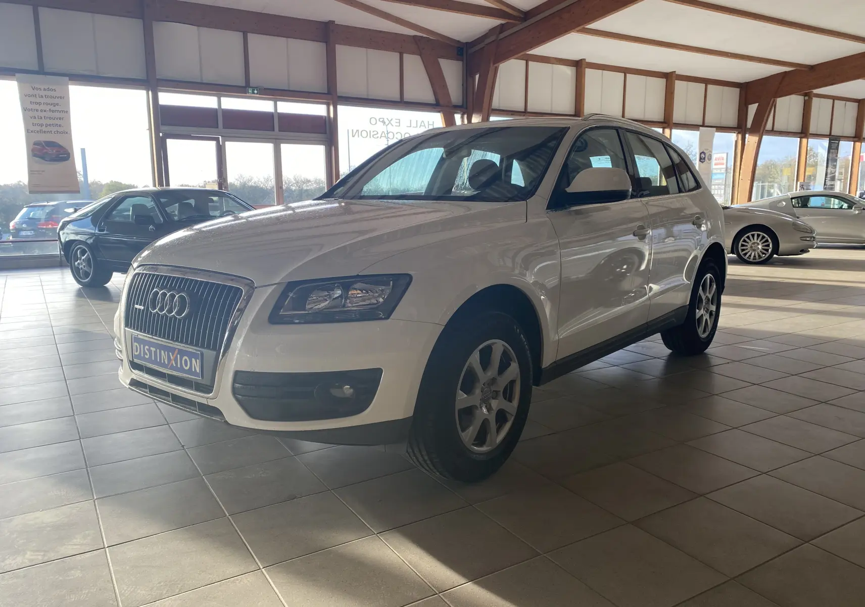 Audi Q5 blanc vue 3/4 avant droit dans un showroom lumineux avec jantes alliage et calandre chromée.