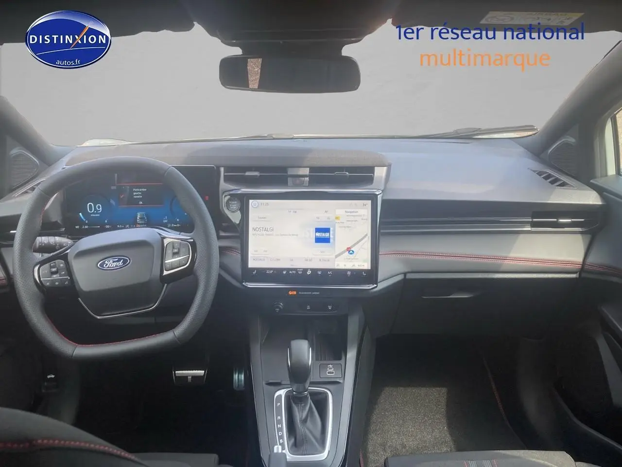 Vue intérieure avant du Ford Puma 2025 gris cactus, avec volant multifonction, écran tactile central et surpiqûres rouges sur les sièges.