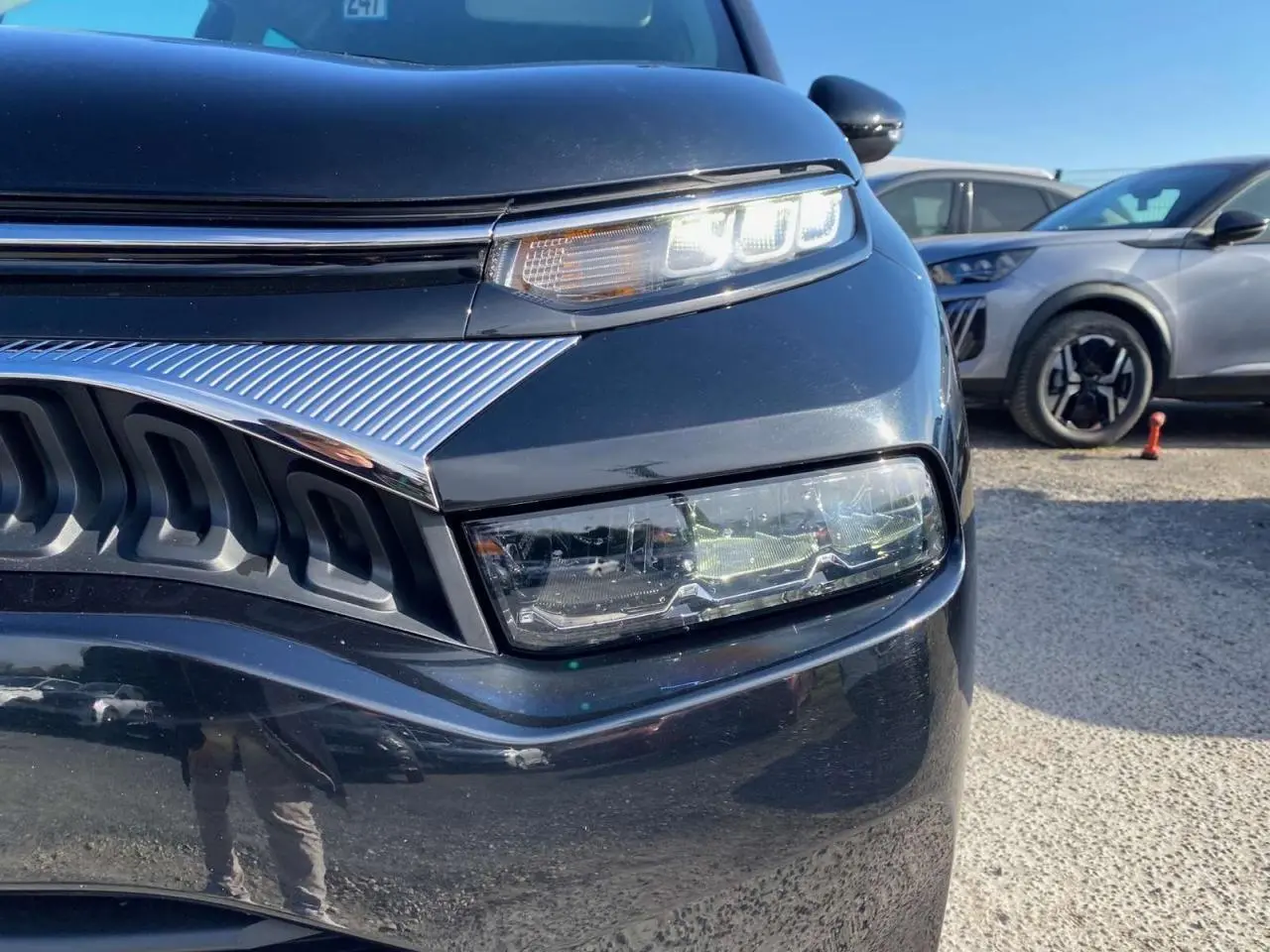 Gros plan sur l'avant droit du Citroën C3 Aircross noir 2023, mettant en valeur ses phares LED et la calandre chromée.