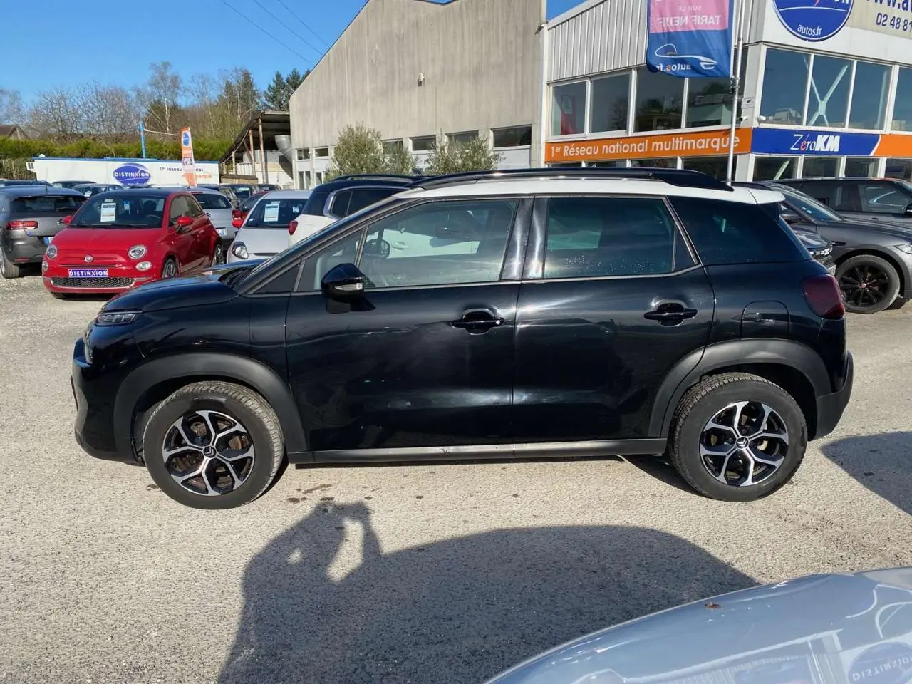 Profil côté gauche d'un Citroën C3 Aircross noir 2023 avec jantes alliage diamantées sur un parking extérieur.
