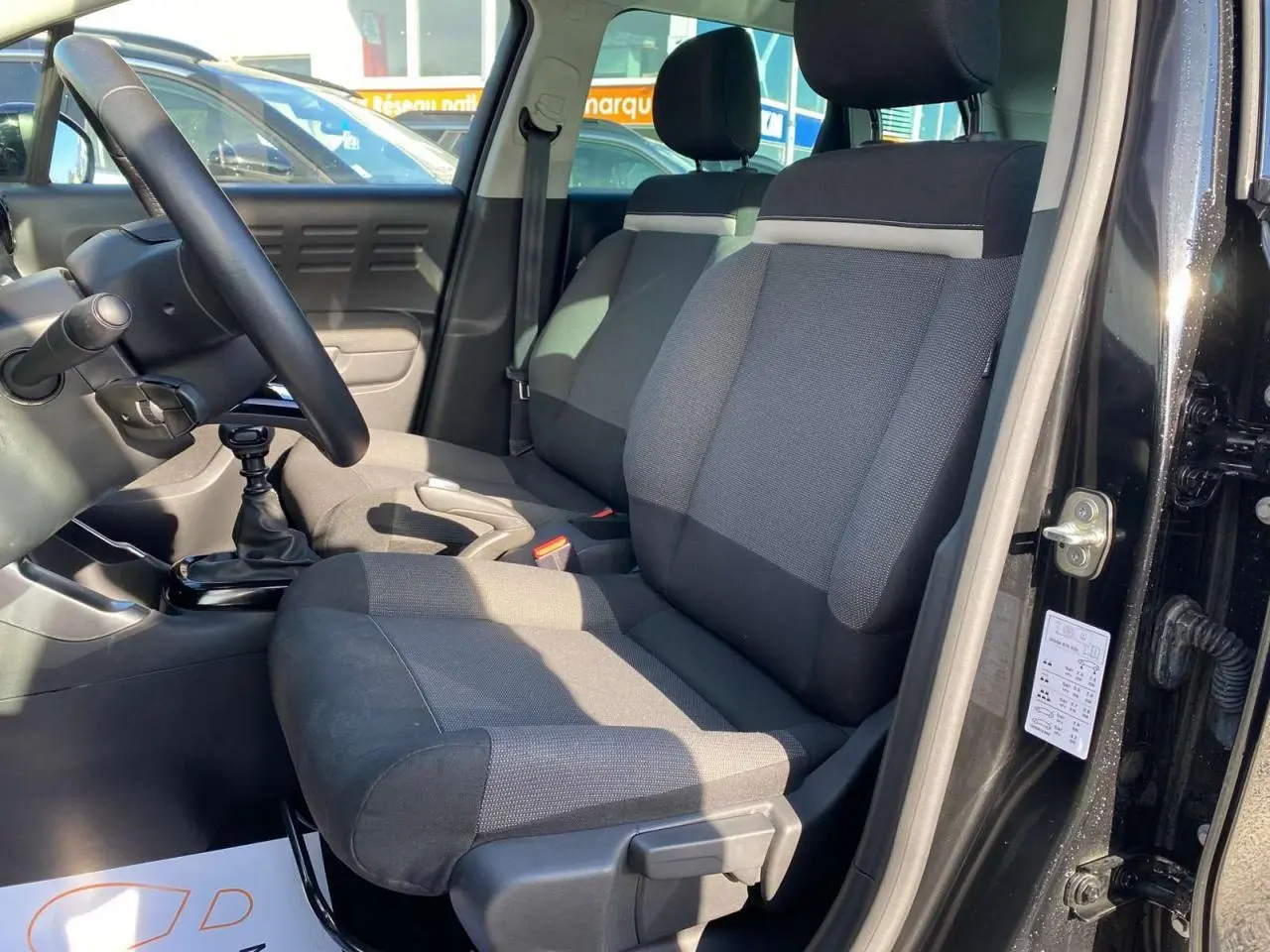 Vue intérieure côté conducteur du Citroën C3 Aircross noir 2023, montrant siège tissu bicolore et volant cuir.