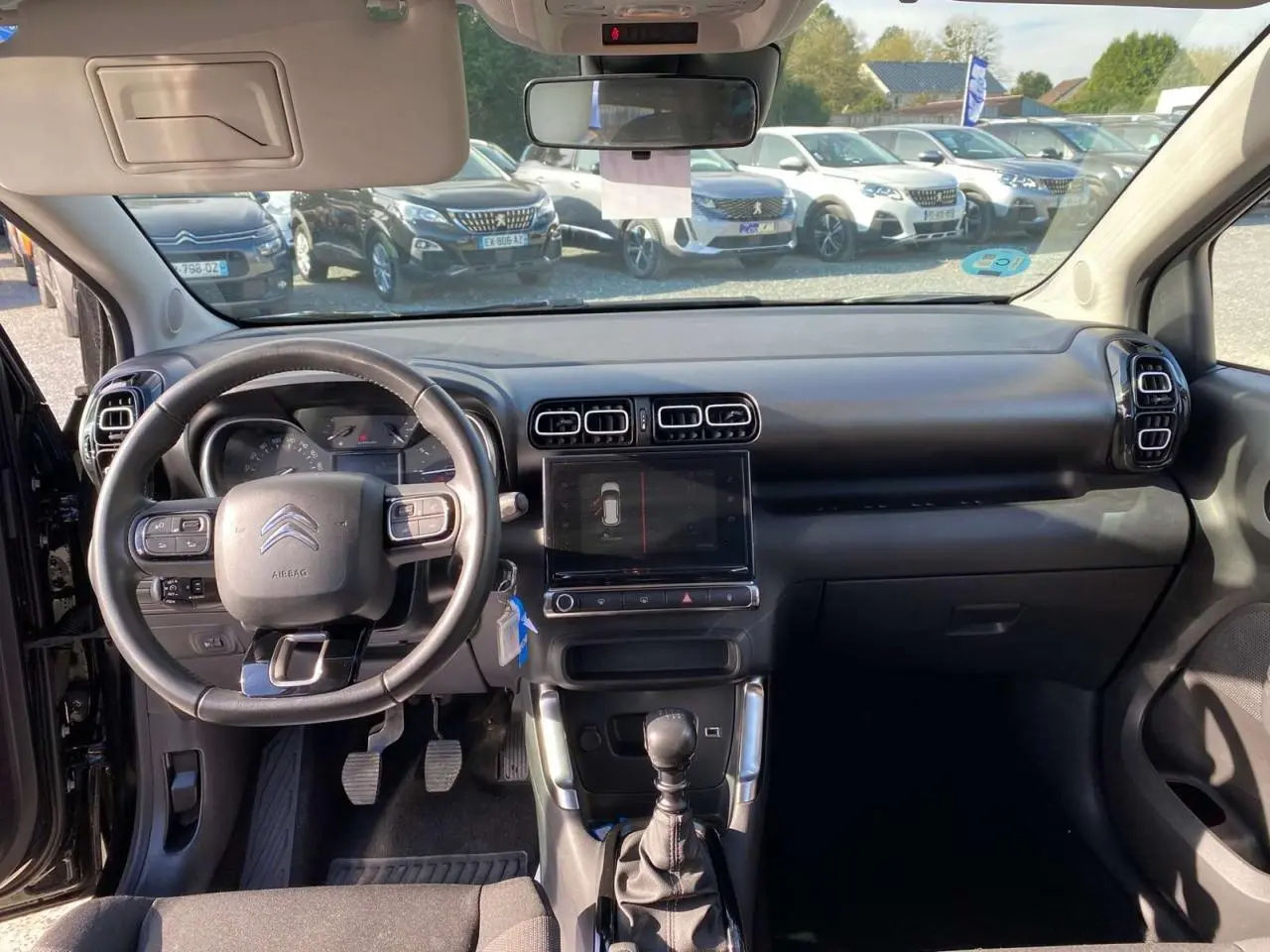 Vue intérieure avant du Citroën C3 Aircross noir 2023, volant cuir, écran tactile et levier de vitesse manuel visibles.