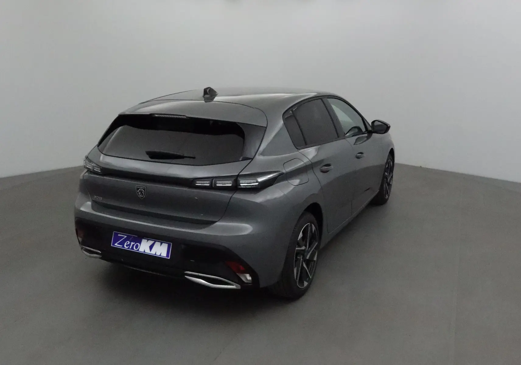 Peugeot 308 gris Sellenium vue 3/4 arrière droit dans un studio, avec vitres teintées et jantes alliage.