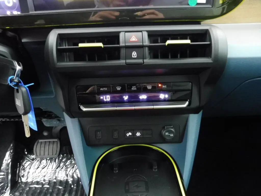 Vue rapprochée du tableau de bord bleu et noir de la Fiat Grande Panda 2025 avec commandes climatisation et prise 12V.