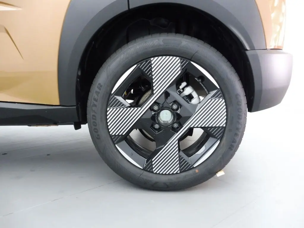 Gros plan sur la roue avant gauche de la Fiat Grande Panda 2025 en bronze luna, avec jante noire et motifs diagonaux blancs.