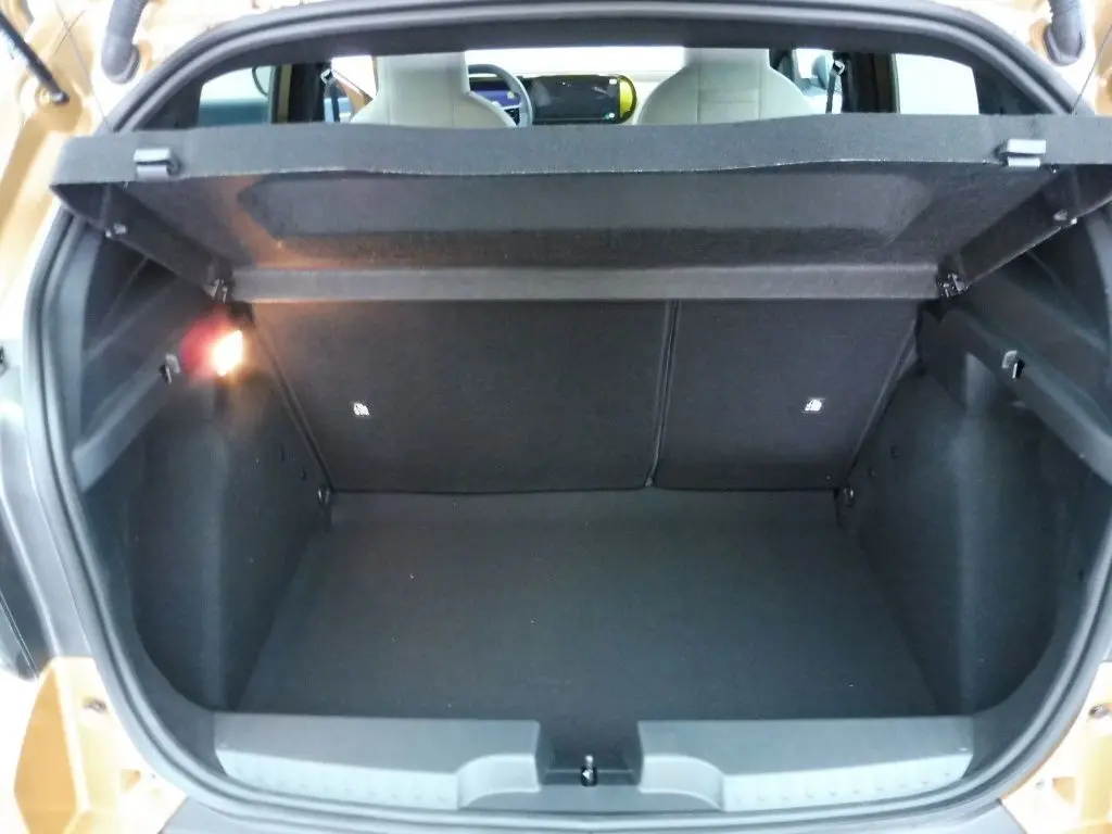 Coffre ouvert vu de l'arrière d'une FIAT Grande Panda 2025 bronze Luna, montrant un espace de chargement vide et éclairé.