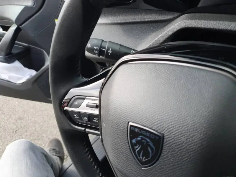 Gros plan sur le volant multifonction noir de la Peugeot 308 2024, avec logo lion et commandes intégrées.