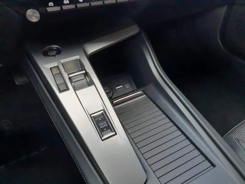 Gros plan sur la console centrale grise du Peugeot 308 2024 avec sélecteur de mode de conduite et bouton start/stop.