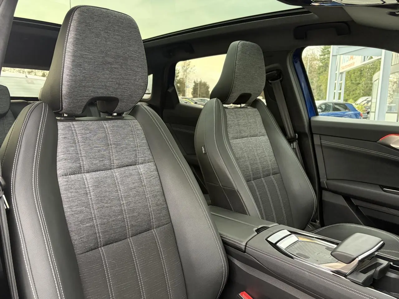 Vue intérieure des sièges avant gris tissu et cuir noir du Renault Austral E-Tech 2025 avec toit panoramique visible.