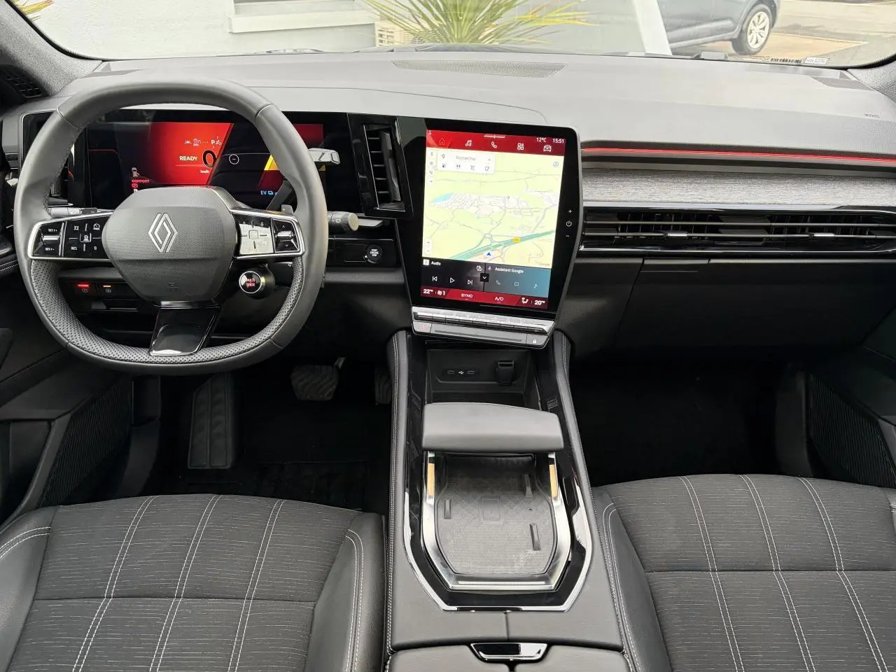 Vue intérieure avant du Renault Austral E-Tech 2025, tableau de bord noir avec écran tactile vertical et volant multifonction.