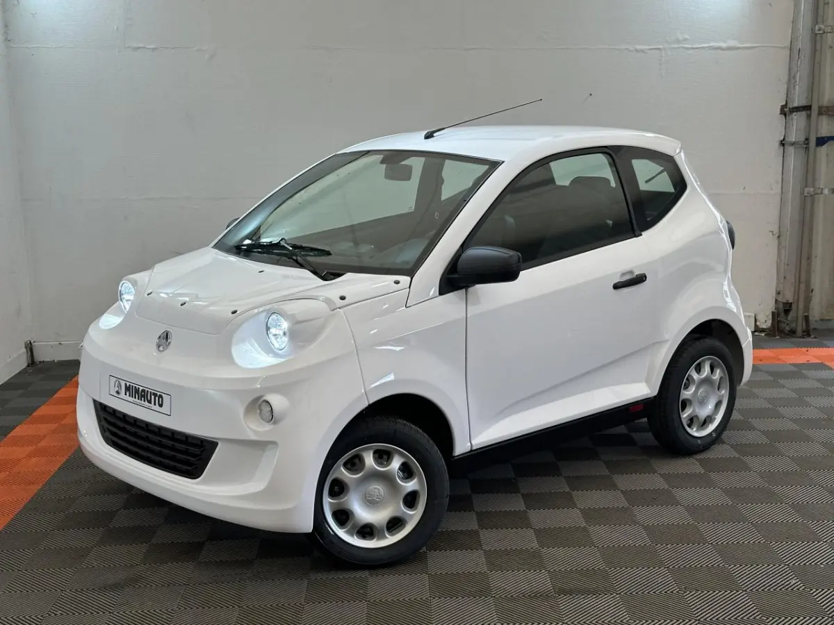 Vue 3/4 avant droit d'une Aixam Minauto E Access blanche avec rétroviseur caméra côté conducteur.