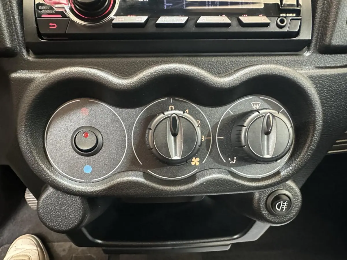 Gros plan sur les commandes de climatisation noires de l'Aixam Minauto E Access 2026, avec boutons rotatifs et bouton antibrouillard.