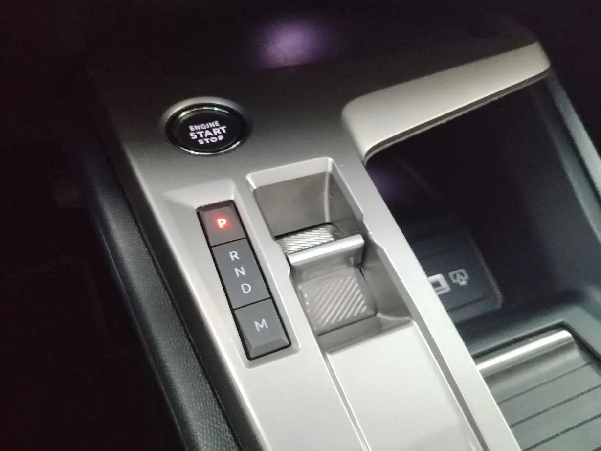 Vue rapprochée de la console centrale grise avec bouton start/stop et commandes de boîte automatique sur Peugeot 308 SW Hybrid.