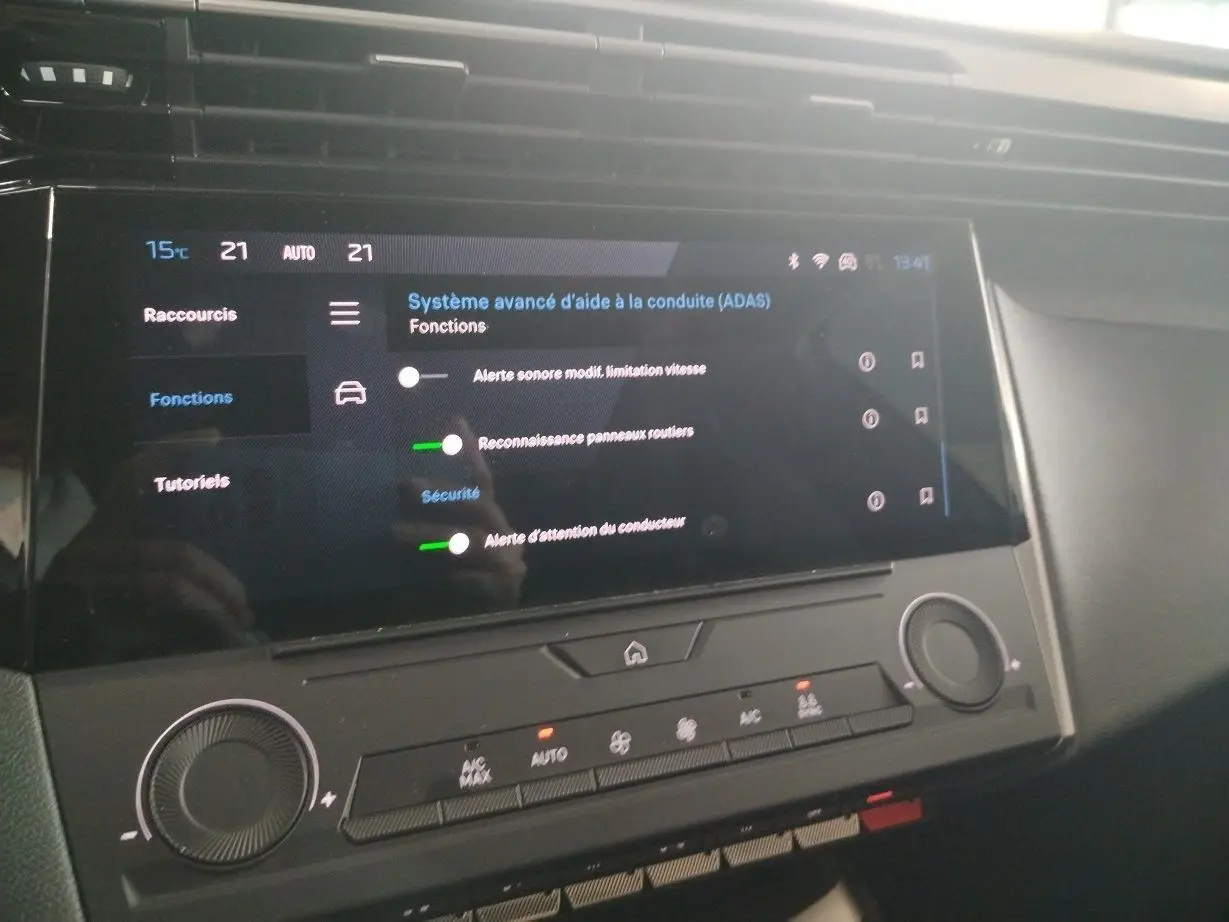 Vue rapprochée de l’écran tactile central du Peugeot 308 SW Hybrid 145 gris Artense, affichant les réglages d’aide à la conduite.