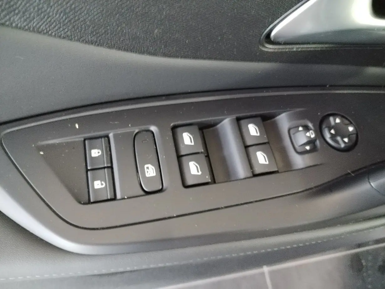 Gros plan sur les commandes des vitres et des rétroviseurs côté conducteur du Peugeot 308 SW Hybrid 2025, finition noire.