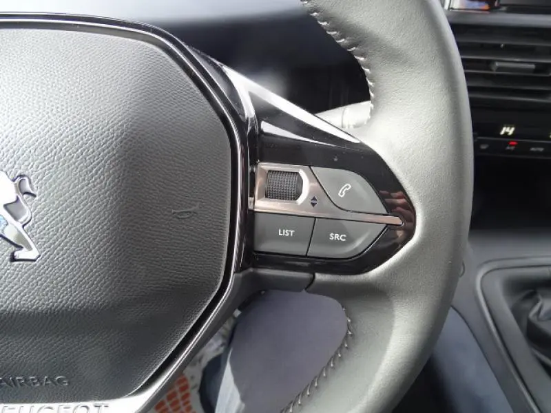 Gros plan sur le volant cuir noir du Peugeot Rifter gris Artense 2019, avec commandes audio intégrées côté droit.