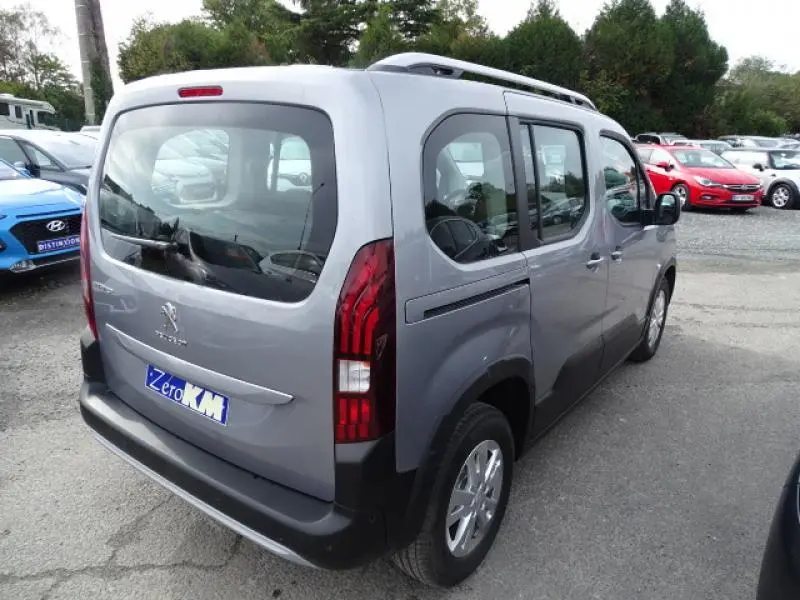 Vue 3/4 arrière droite d'un Peugeot Rifter 2019 gris Artense avec hayon vitré et feux arrière verticaux rouges.